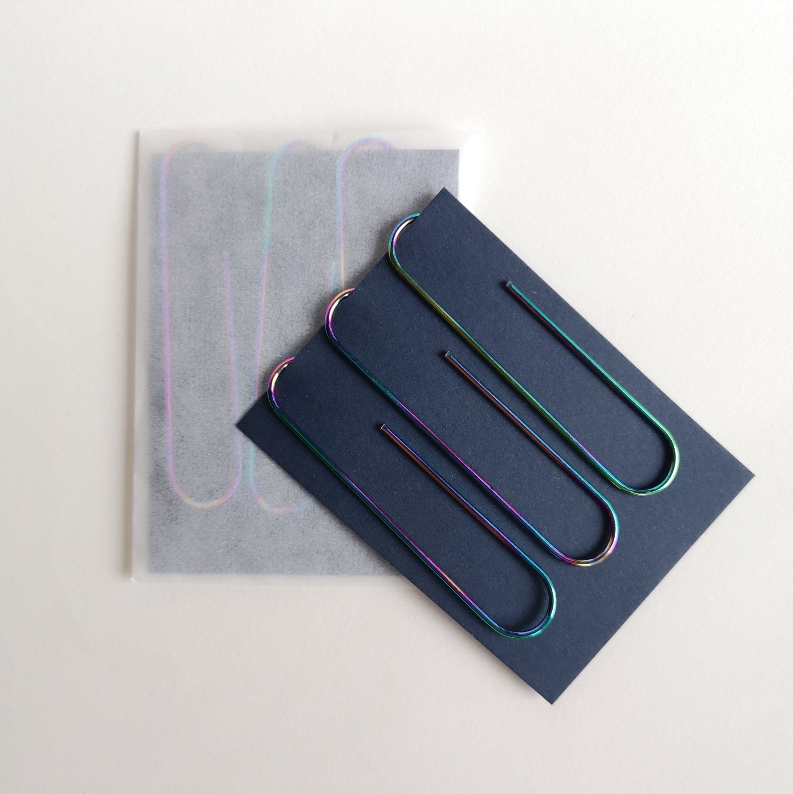 Three giant metallic clips on navy card